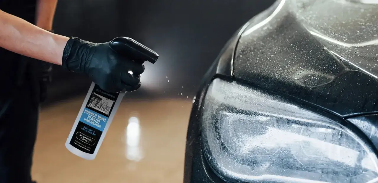 En hand med svart handske sprayar en bil med en produkt för gummi, vinyl och plast. VRP-formulan ger nytt liv åt torra ytor.