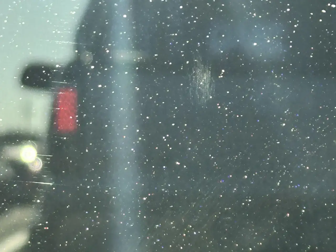 Smutsiga rutor med reflektioner av ljus och en r&ouml;d baklykta. Glaspolish beh&ouml;vs f&ouml;r att f&aring; bort repor och smuts.
