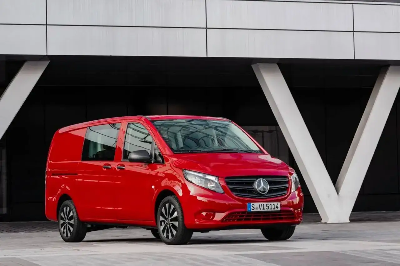 Röd Mercedes Vito står parkerad framför en modern byggnad. Inga problem syns med bilen.